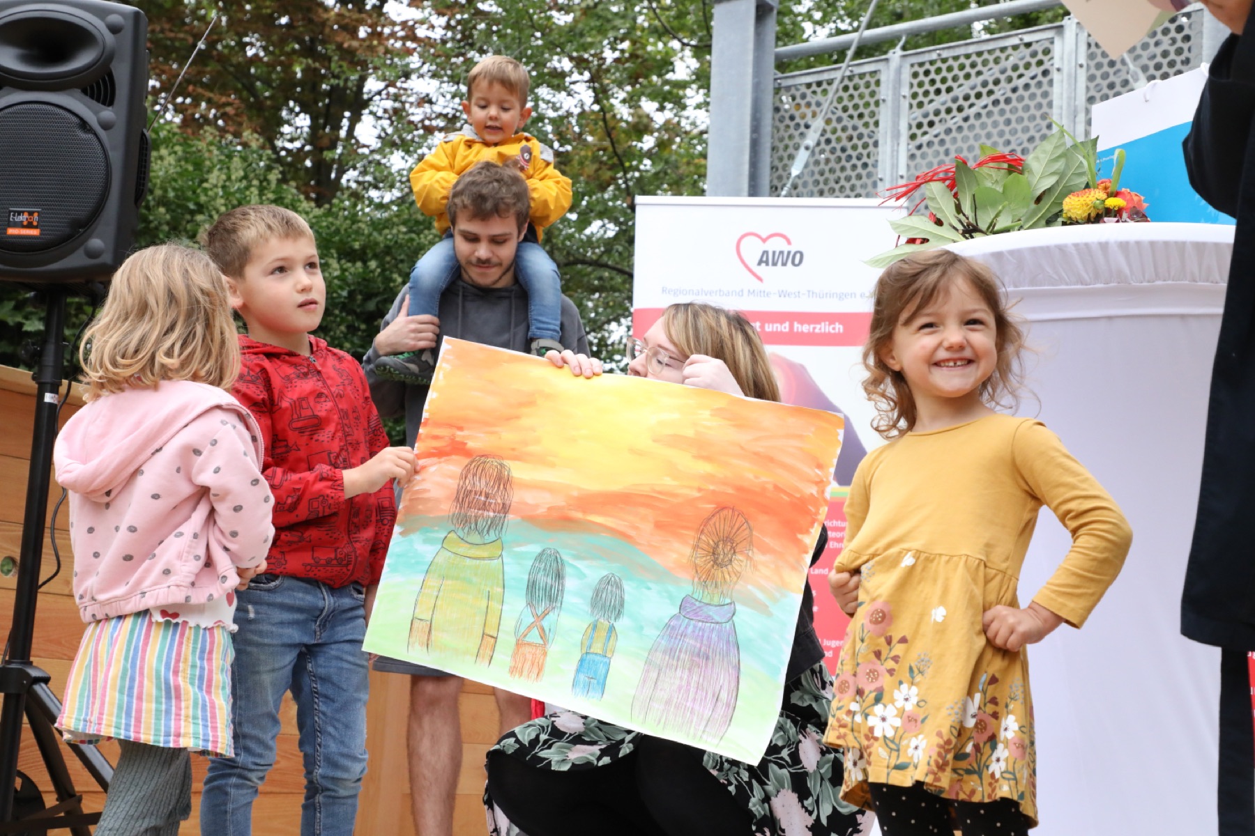 Kinder zeigen lachend ein selbst gemaltes Bild bei einem Fest der AWO